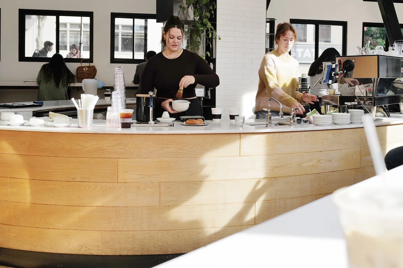 Baristas working behind the curved wood counter at Réveille Coffee in North Beach.